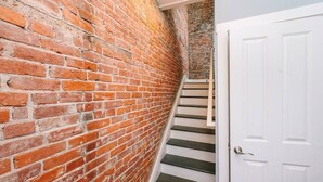 Un muro de ladrillo, una puerta blanca y una escalera.
