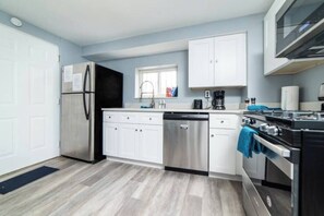 A modern kitchen with white cabinets, stainless steel appliances, and a blue towel hanging on the oven handle.