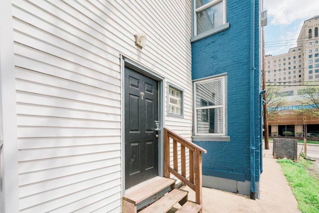 A two-story building with a black front door and a wooden staircase leading to the entrance.