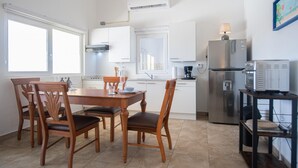 A modern kitchen with white cabinets, a stainless steel refrigerator, and a dining area with wooden chairs and a table. - NEW Casa Orcuyo in Santa Cruz (Santa Cruz)