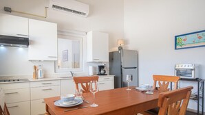 A modern kitchen with white cabinets, a wooden dining table, and a built-in oven. - NEW Casa Orcuyo in Santa Cruz (Santa Cruz)