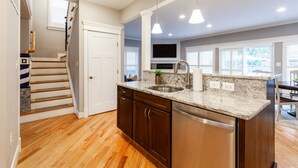 Una cocina moderna con suelo de madera, armarios oscuros y un lavavajillas de acero inoxidable.