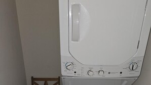 A compact laundry room with a washing machine and dryer stacked vertically. - Modern, Convenient Gem: Urban Retreat 'n Richmond (Richmond)