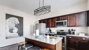 A modern kitchen with dark wood cabinets, stainless steel appliances, and a marble island. - Modern, Convenient Gem: Urban Retreat 'n Richmond (Richmond)