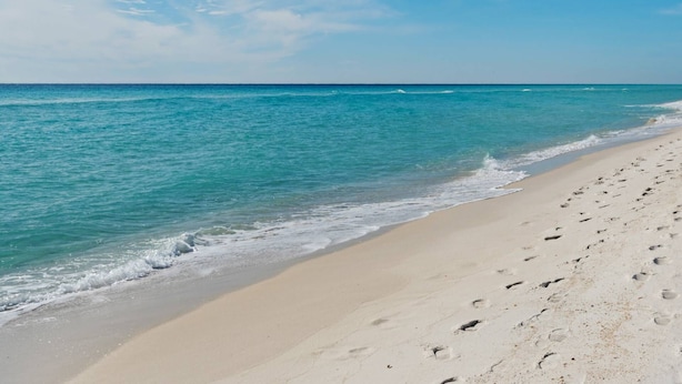 A beach with clear turquoise water and a sandy shore.
