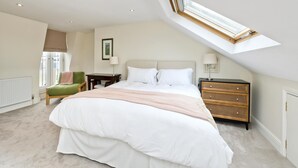 A bedroom with a large bed, a desk, a chair, a nightstand, and a skylight. - Family Home near Clapham Common (London)