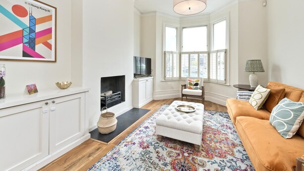 A modern living room with a fireplace, a sofa, a television, and a large window. - Family Home near Clapham Common (London)