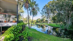 A serene outdoor area with a water feature, lush greenery, and a covered seating area. - Lily Pad Beach House (Agnes Water)