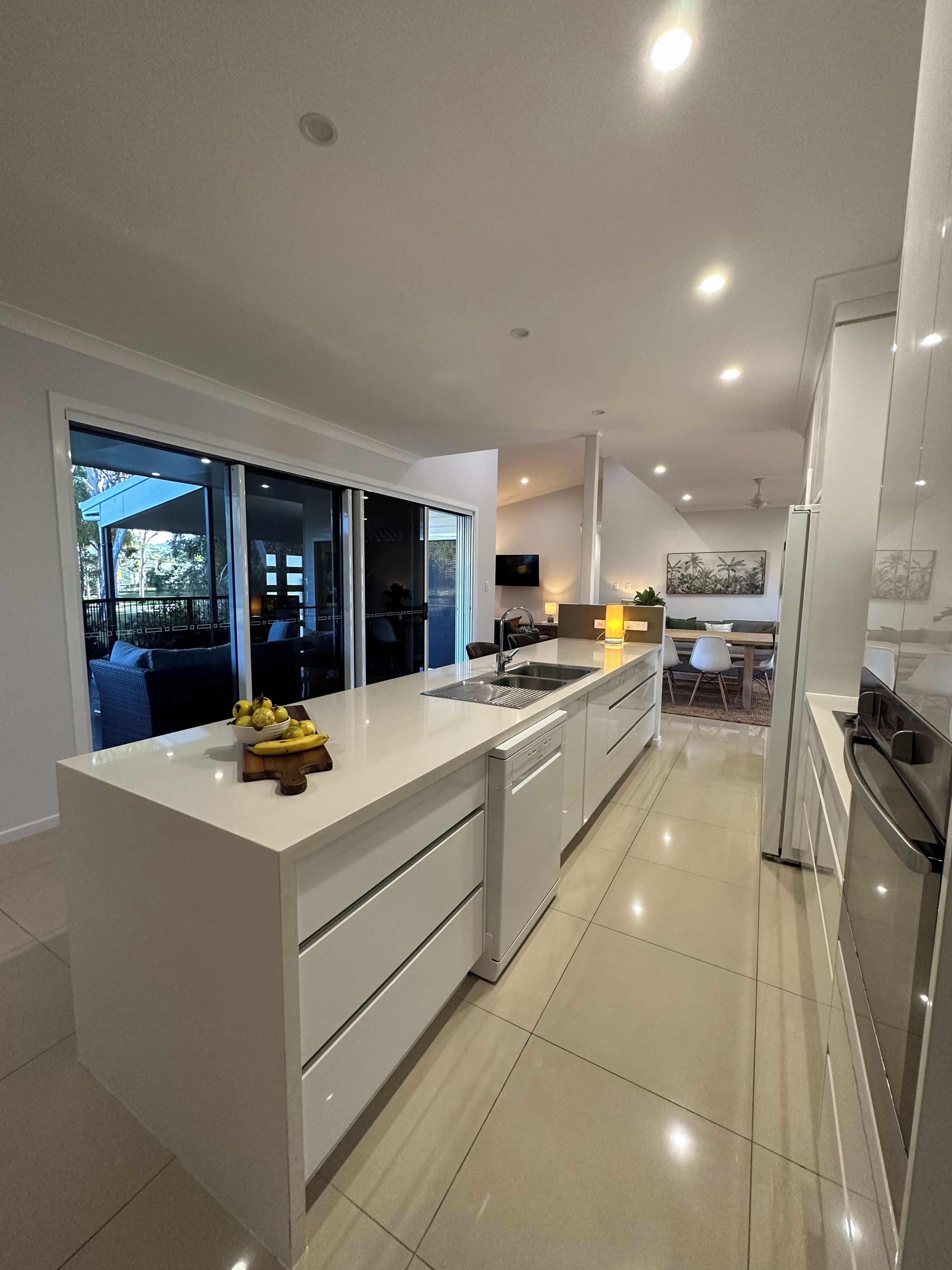 A modern kitchen with a large island, built-in appliances, and a view to an outdoor area.