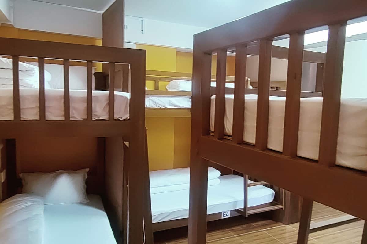Camas literas en una habitación con paredes amarillas y piso de baldosas.