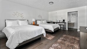 A modern hotel room with two beds, a desk, a kitchenette, and a bathroom. - TC Wine Country Stay | Near Beach + Sleeps 4 (Traverse City)