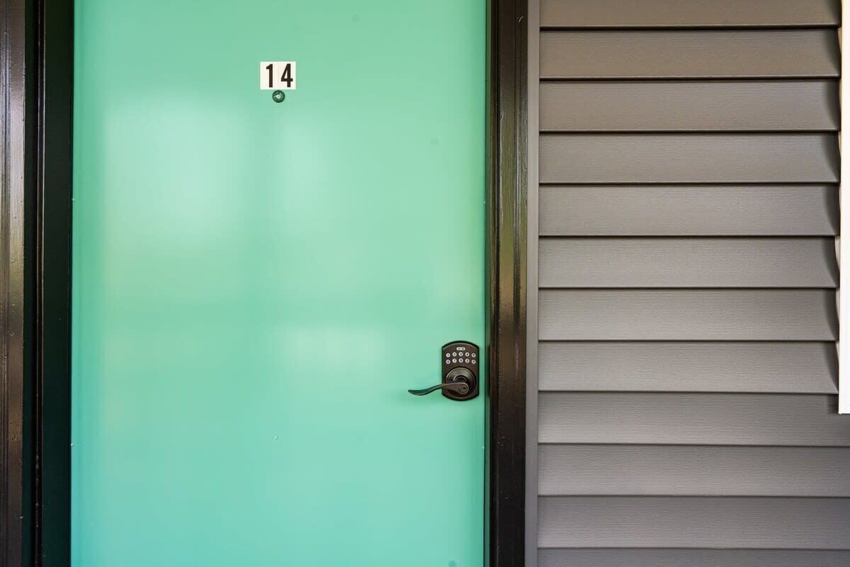 A teal door with a numeric keypad lock, number 14, and a metal frame.