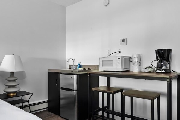 A compact kitchenette with a microwave, coffee maker, and refrigerator. - King Studio TC | Near Downtown + Near beach (Traverse City)