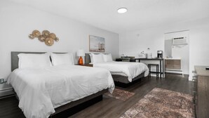 A modern hotel room with two beds, a desk, a chair, a microwave, and an air conditioning unit. - Peninsula One Apartments Unit 17 (Traverse City)