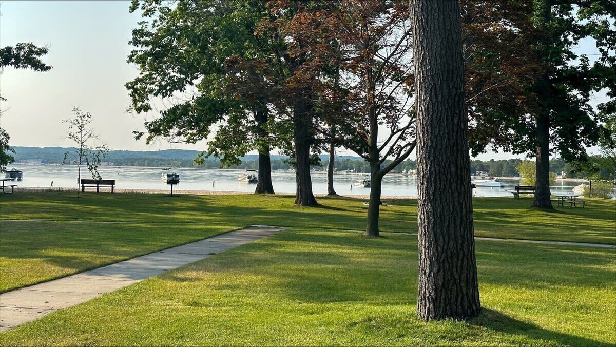A park with a pathway, benches, and trees overlooking a body of water.