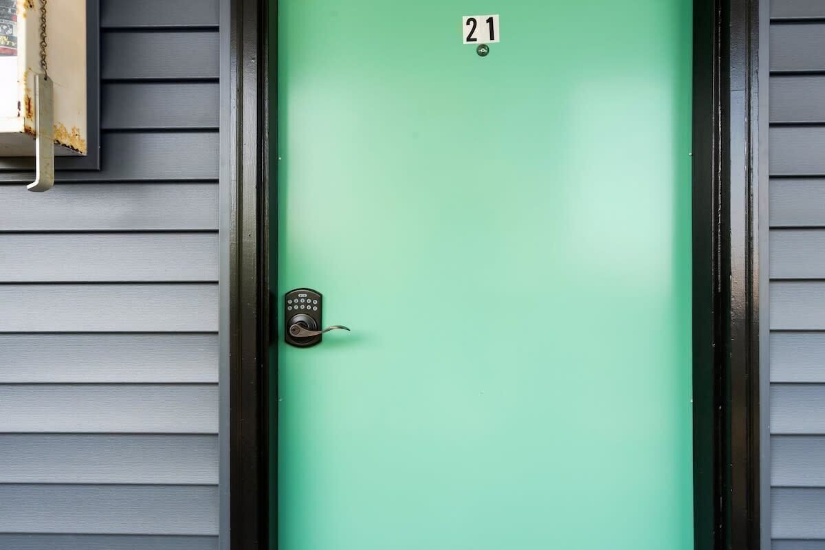 A green door with a keypad lock and the number 21 above it.