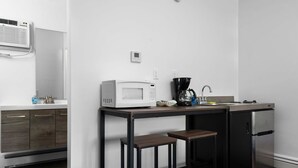 Une cuisine compacte équipée d’un four à micro-ondes, d’une machine à café et d’un petit réfrigérateur.