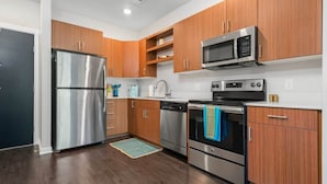 Una cocina moderna con electrodomésticos de acero inoxidable, armarios de madera y un microondas empotrado.