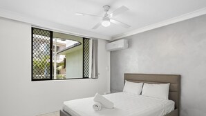 A bedroom with a bed, a ceiling fan, a window with a view, and an air conditioning unit. - Unit 24-24 Hamilton Ave Surfers Paradise (Surfers Paradise)