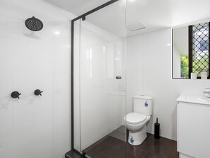 Enjoy a refreshing shower in the bathroom, featuring a glass-enclosed shower, toilet, and sink.