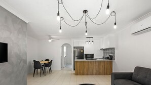 A modern living room with a sofa, a coffee table, and a dining area with chairs and a table. - Unit 24-24 Hamilton Ave Surfers Paradise (Surfers Paradise)