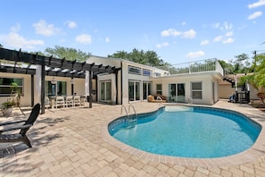 A modern house with a swimming pool, outdoor furniture, and a pergola.