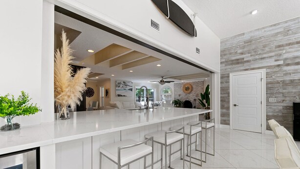 Una cocina moderna con una isla grande, taburetes de bar y una puerta blanca.
