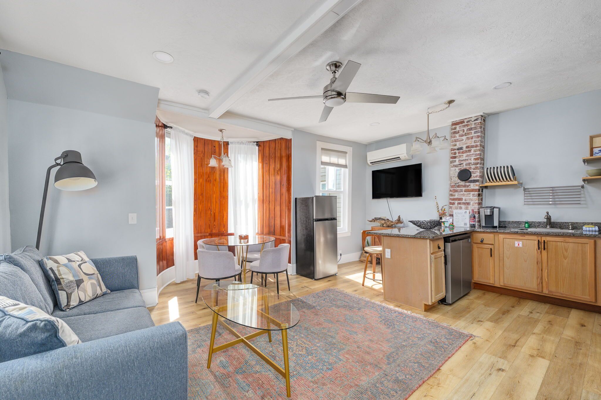 A modern living room with a sofa, a glass coffee table, and a dining area with chairs.