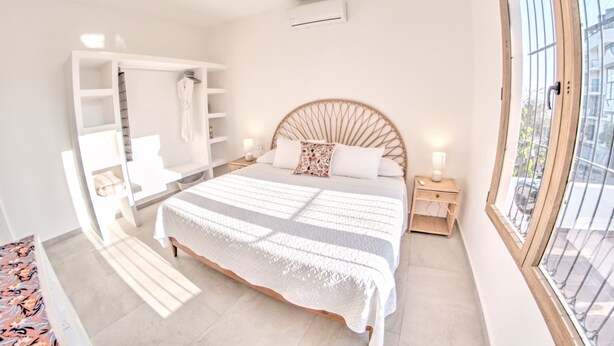 Une chambre à coucher avec un lit, des tables de chevet, une armoire et une fenêtre.
