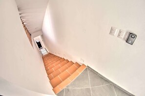 A staircase with orange steps leading to a landing, white walls, and a wall-mounted intercom. - Oceanview Studio 3.5 Blocks to Beach - Upper East (Bucerías)