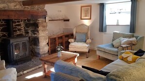 Ein gemütliches Wohnzimmer mit Kamin aus Stein, einem Holztisch und bequemen Sitzgelegenheiten.