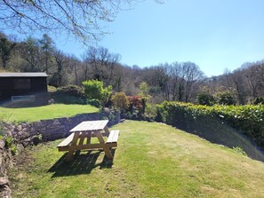 A picnic table in a grassy area with a stone wall and a building in the background. - The Old Post Office. A cosy rural gem -  Dartmoor (Ponsworthy)