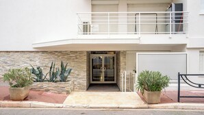 A modern two-story building with a stone facade, a glass entrance, and a balcony with a metal railing. - Le Royal Studio adorable avec terrasse (Cannes)