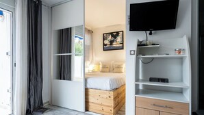 A bedroom with a bed, a TV, and a window with curtains. - Le Royal Studio adorable avec terrasse (Cannes)