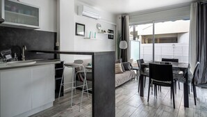 A modern apartment with a kitchen, dining area, and a large window. - Le Royal Studio adorable avec terrasse (Cannes)