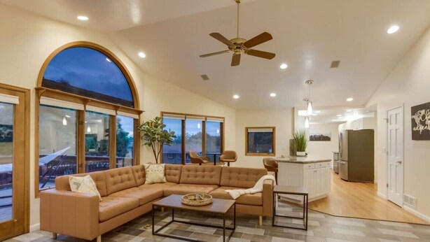 A spacious living area with a large sectional sofa, a coffee table, and a ceiling fan. - Backyard Oasis Pool | Beautiful Home (Arvada)