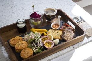 Una bandeja de madera con diversos alimentos, incluyendo frituras, una ensalada y una bebida.