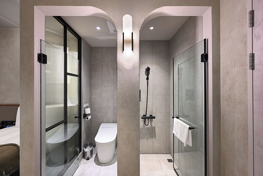 Un baño moderno con ducha envuelta en vidrio, inodoro y tocador con perchero.