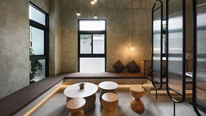 Un intérieur moderne avec un espace salon, des tables rondes et une grande fenêtre.