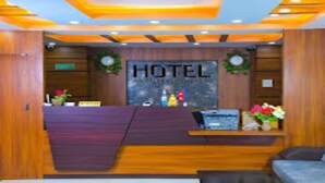 A hotel reception area with a wooden reception desk, a sign reading "HOTEL," and a couch in the foreground.