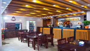A restaurant with wooden ceiling beams, a bar area, and several wooden tables and chairs.