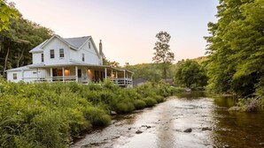 A white house with a porch and a river in front.