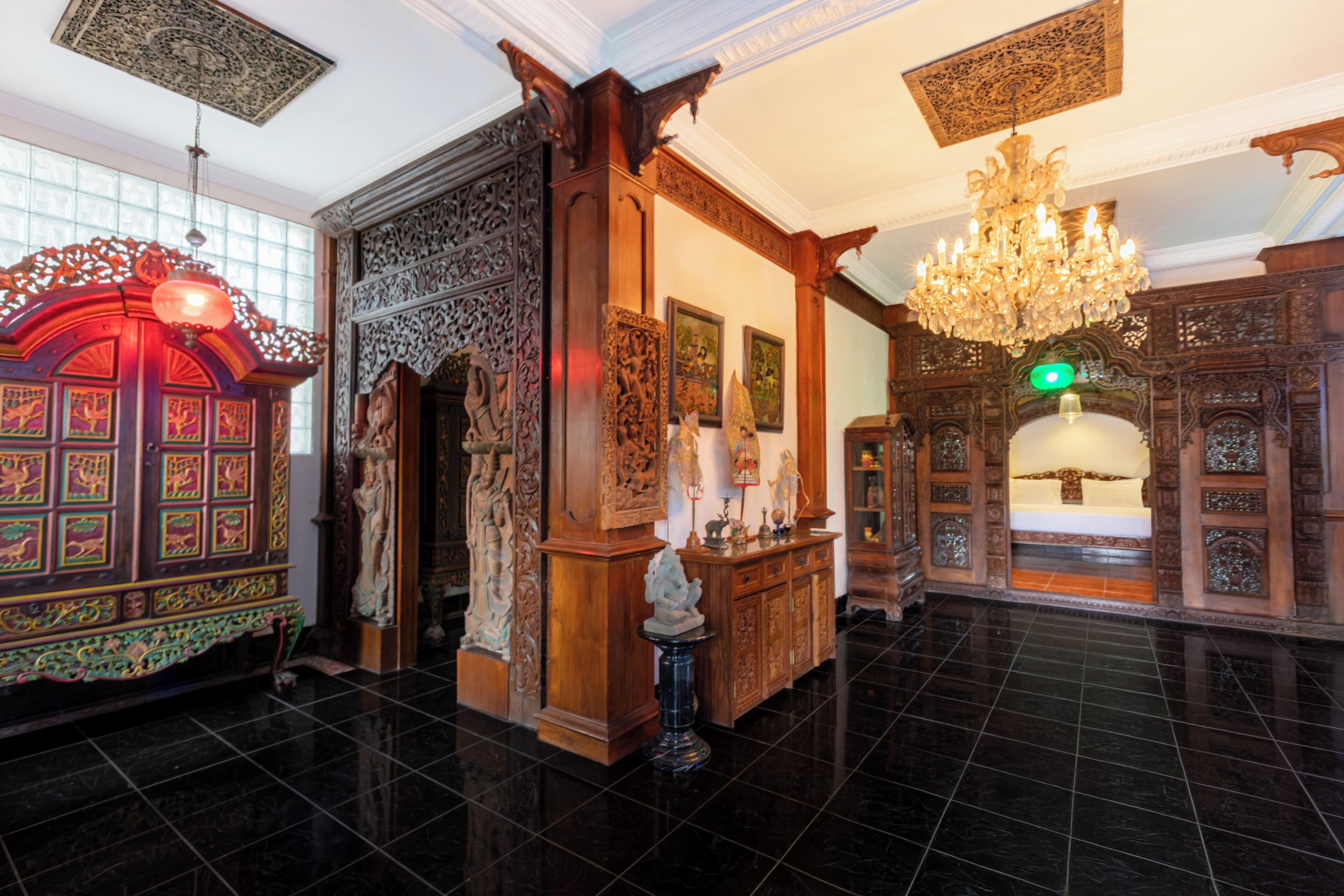 Un hall decorado con un candelabro, detalles de madera tallada y una estatua.