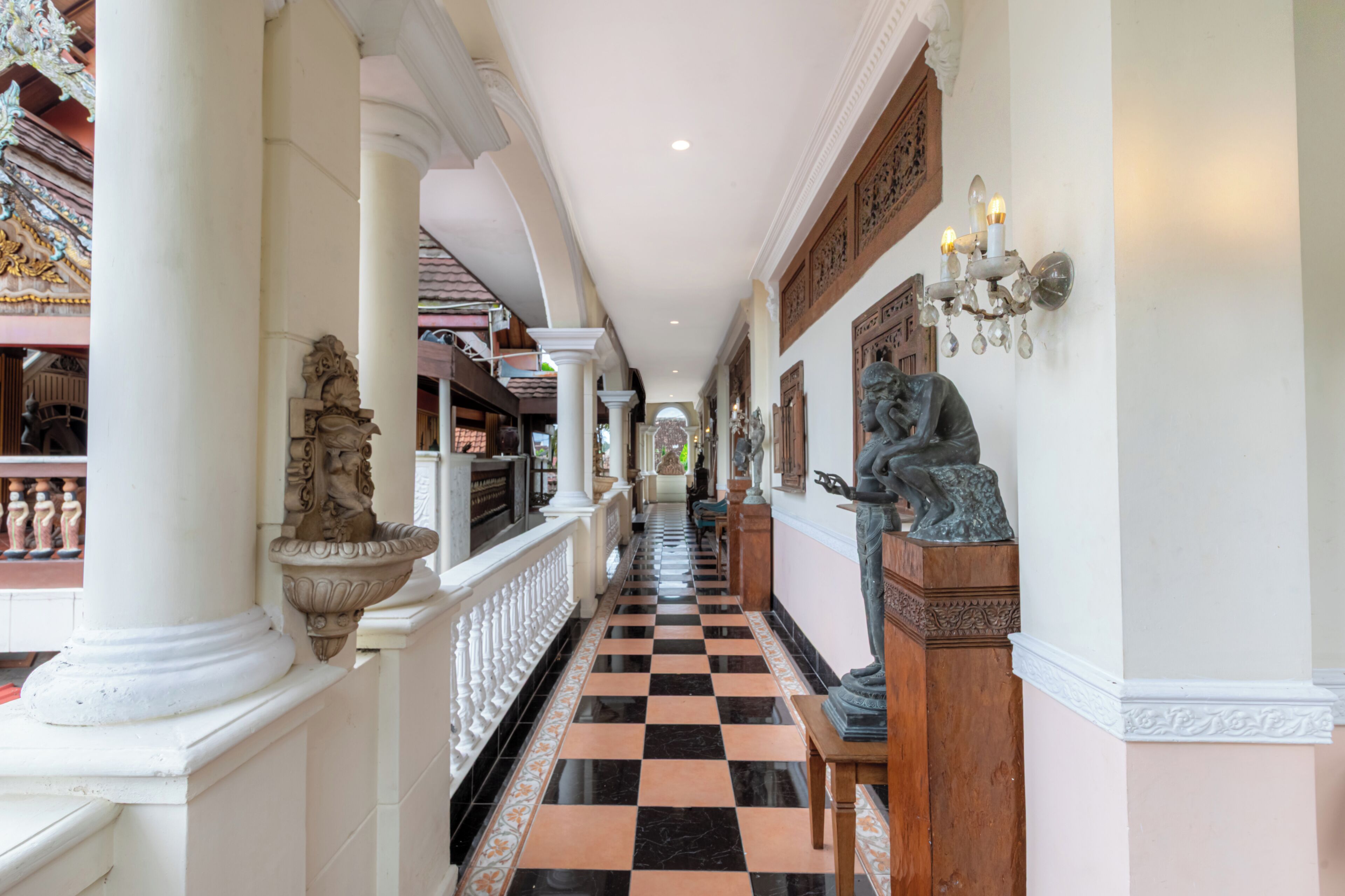 A corridor with columns, a checkered floor, and statues.
