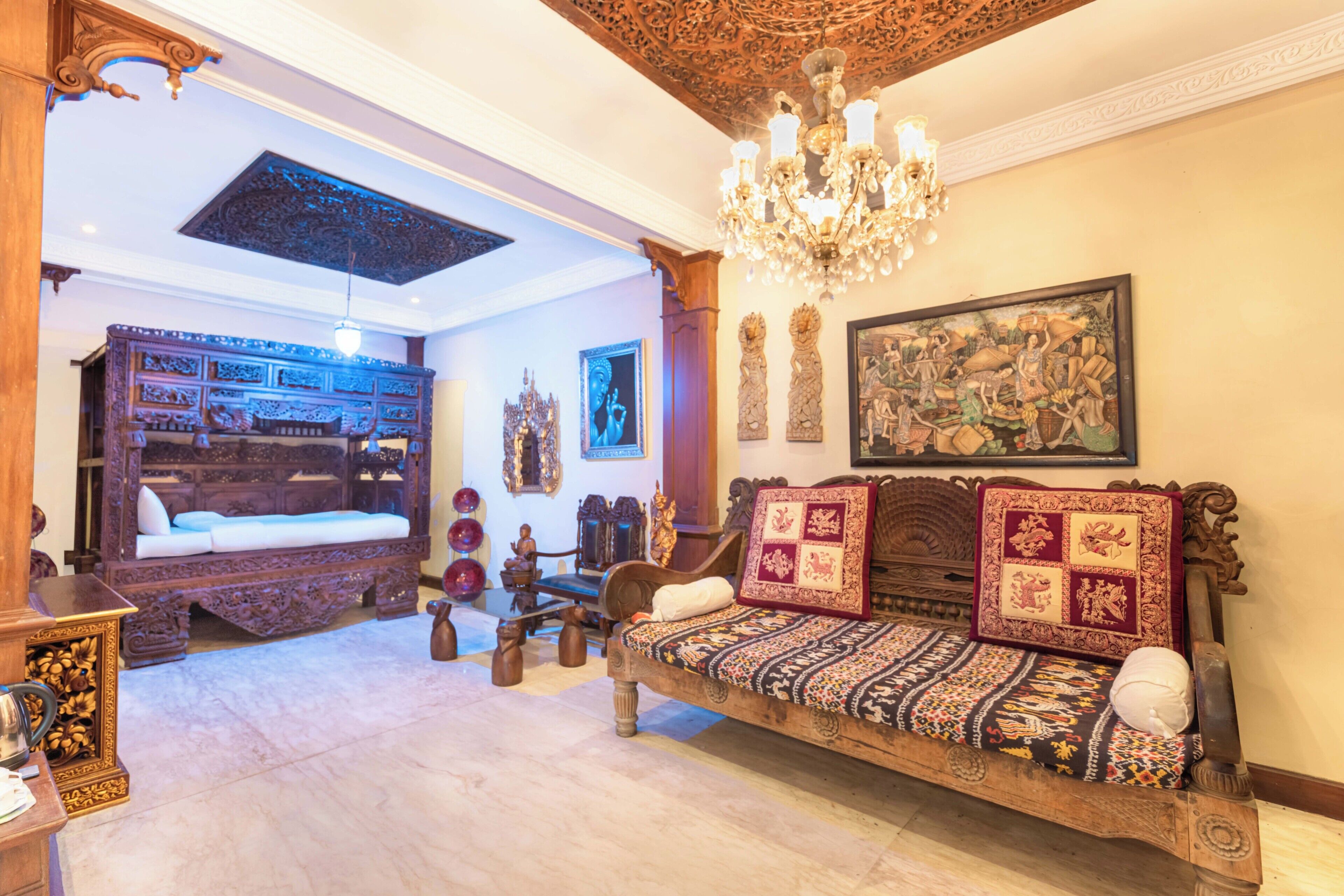 A traditional room with a wooden sofa, ornate ceiling, and a chandelier.