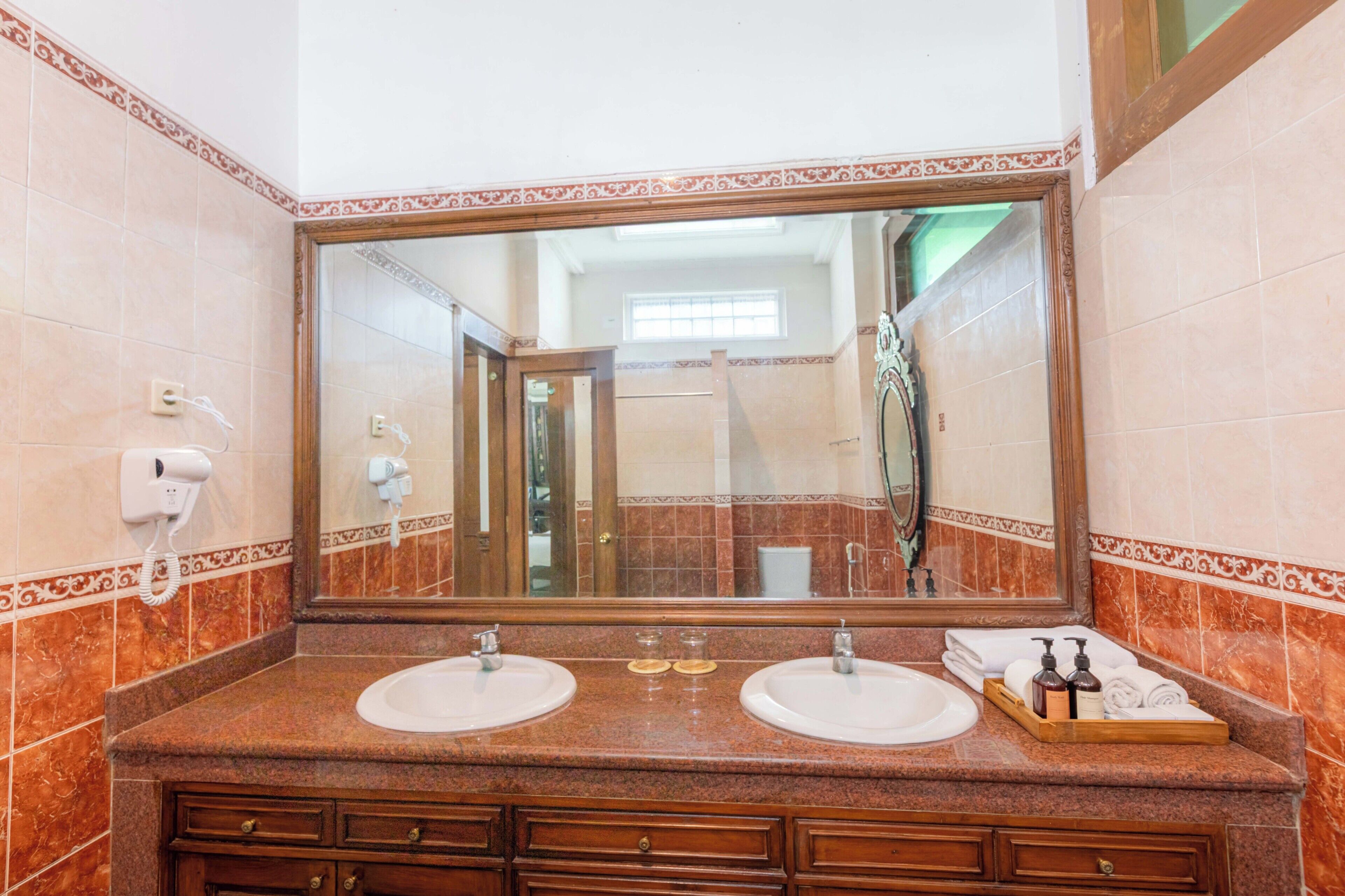 Un baño con dos lavamanos, un espejo grande y un mueble de tocador con cajones.