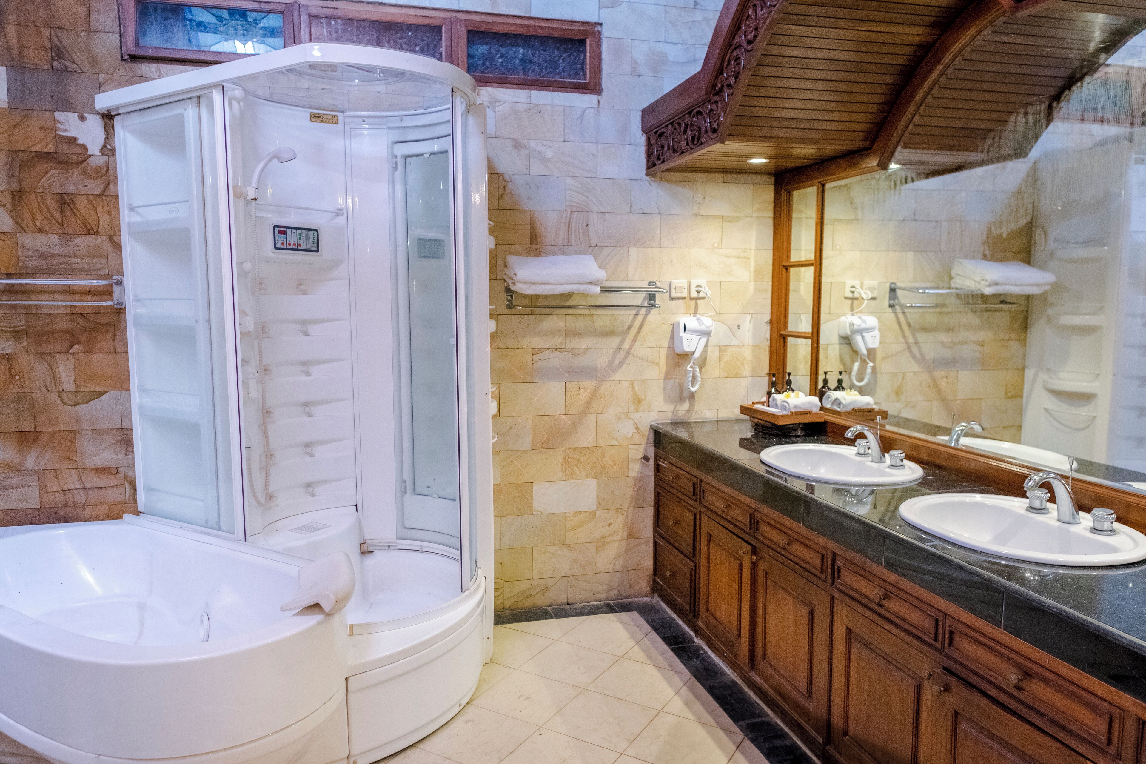 Ein Badezimmer mit begehbarer Dusche, einer Badewanne und zwei Waschbecken mit Spiegeln.