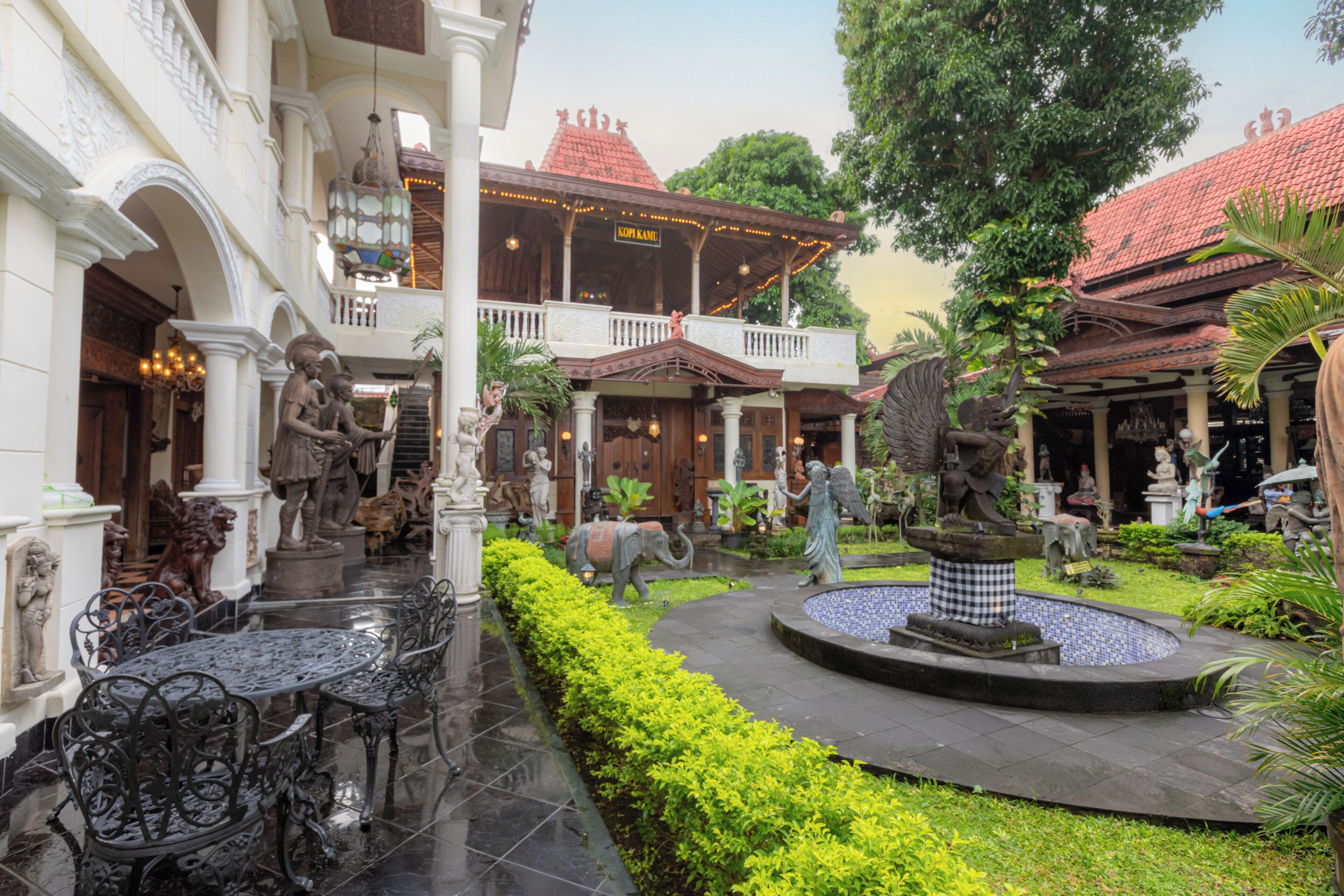 A courtyard with a fountain, statues, and outdoor seating.