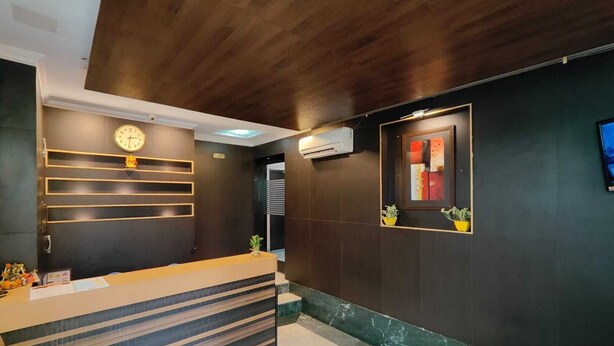 Un espace d’accueil au design moderne, comprenant un comptoir de réception, une horloge et une œuvre d’art encadrée accrochée au mur.