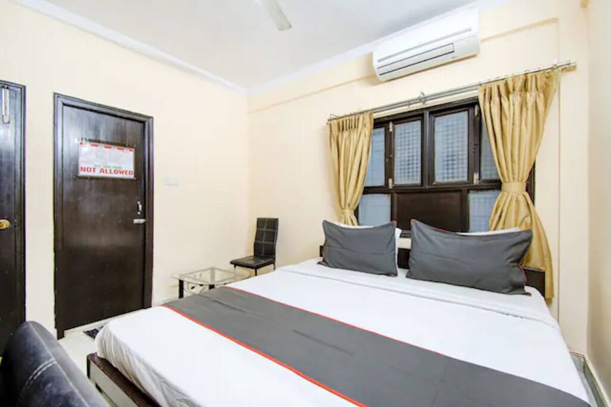Quarto de hotel com uma cama, uma cadeira, uma escrivaninha e uma porta com o aviso 'NÃO PERMITIDO'.